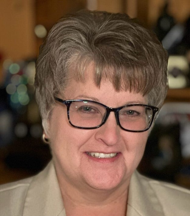 Photo of smiling woman with short hair and glasses.