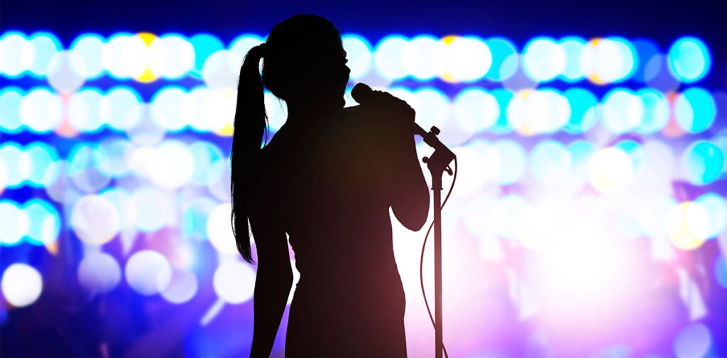 Silhouette of female singer on-stage with bright lights in the background