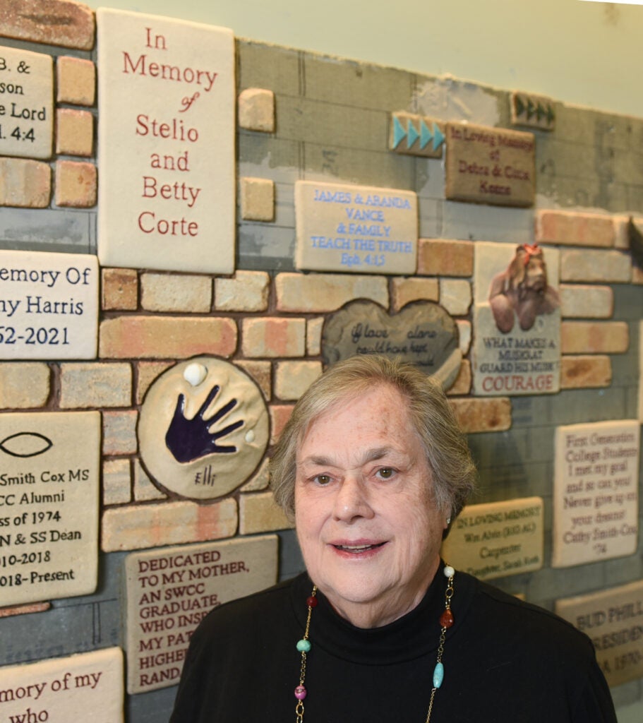 Cathy Payne stands for a photo in front of a brick in memory of her parents, Stelio and Betty Corte. The new brick donor wall is located inside Dellinger Hall.