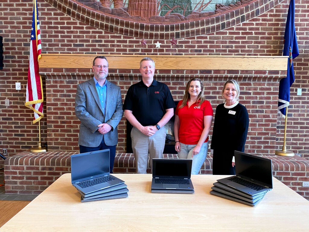 (L-R) President Clint Hayes, Bruce Crowder, Taylor Robinson, and Susan Lowe standing behind 10 donated laptops.