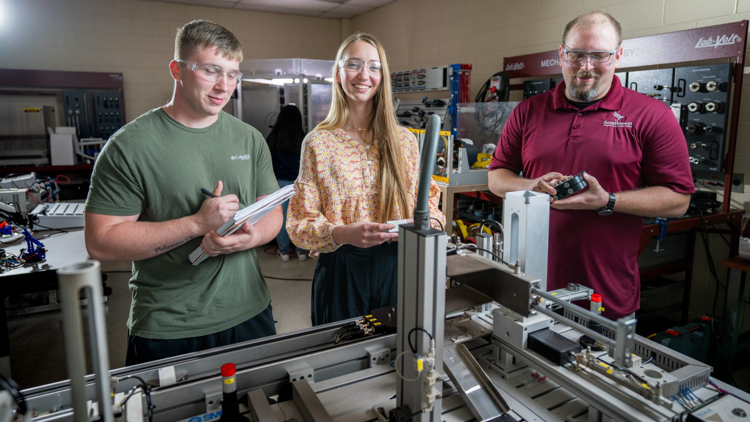 Two students and an instructor configuring a machine in the mechatronics lab.