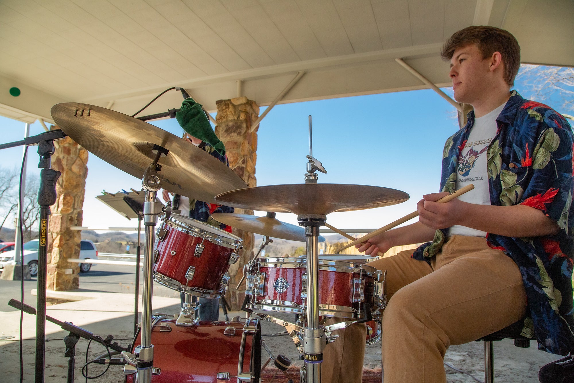 male student playing red drum set